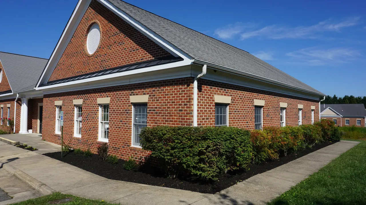 Shrubs and dark mulched beds around a brick commercial building.